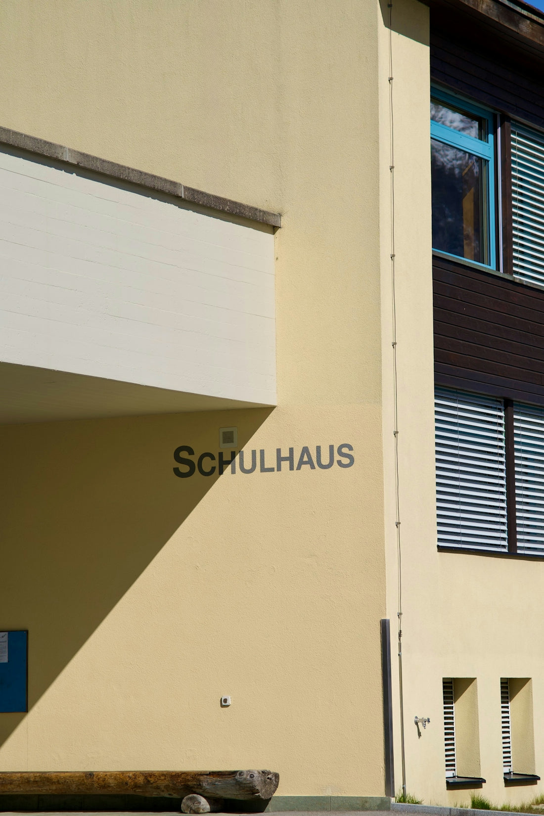 A yellow school building wall with the word SCHULHAUS in dark lettering
